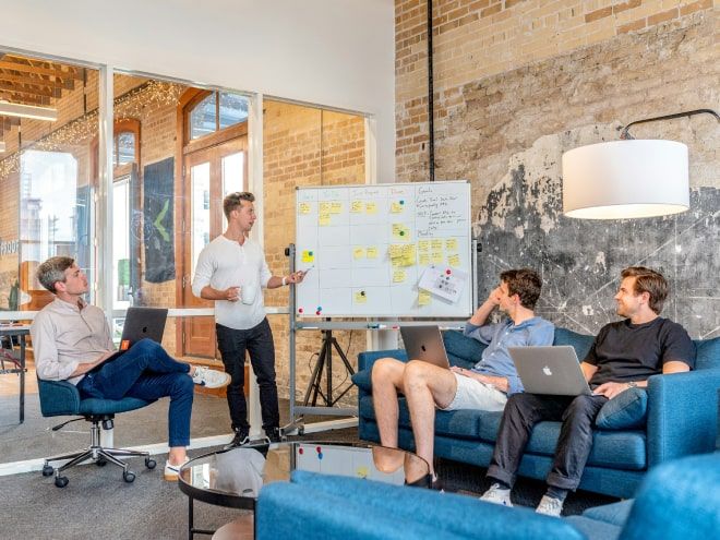 A tech team brainstorming in a modern office environment with a whiteboard presentation on project management, showcasing agile methodology and collaborative work.