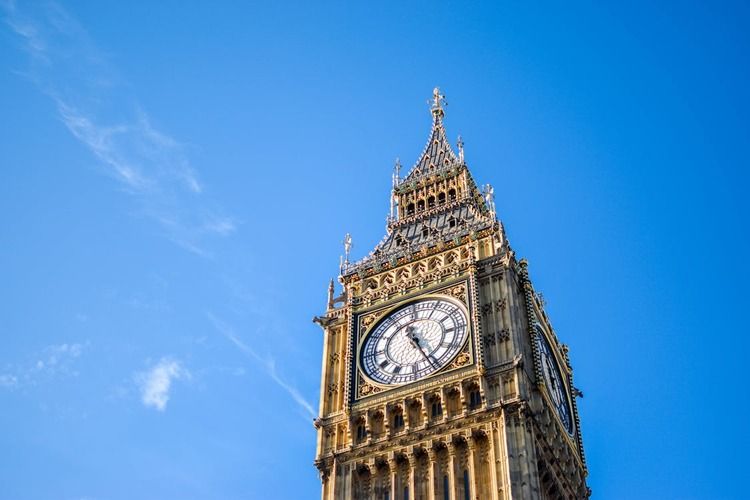 The Elizabeth Tower, home to the Big Ben bell, set against a clear blue sky in London, with intricate gothic architectural details visible on its facade, highlighting a symbol of British culture and heritage.