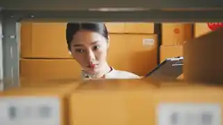What you don't know can hurt you Focused employee checking inventory in a storeroom, with her gaze directed towards a clipboard, framed by shelves lined with organised brown cardboard boxes, suggesting an efficient business operation.
