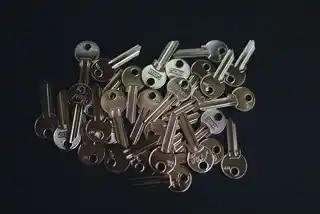 The unseen battle of password management A pile of assorted metal keys with various cuts and brands scattered on a dark background, representing the concept of security, access, and password management.
