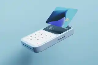 Contactless payment card hovering over a modern card reader on a blue background, illustrating cashless transactions.