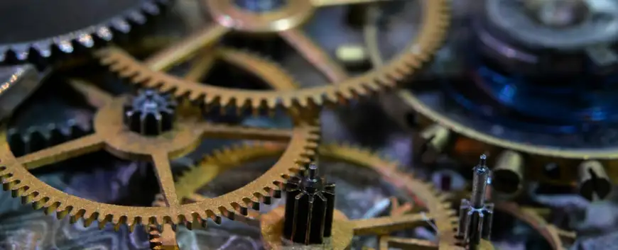Close-up of intricate bronze and steel gears and cogs within a mechanical device, symbolising precision engineering, complexity, and reliability in machinery.